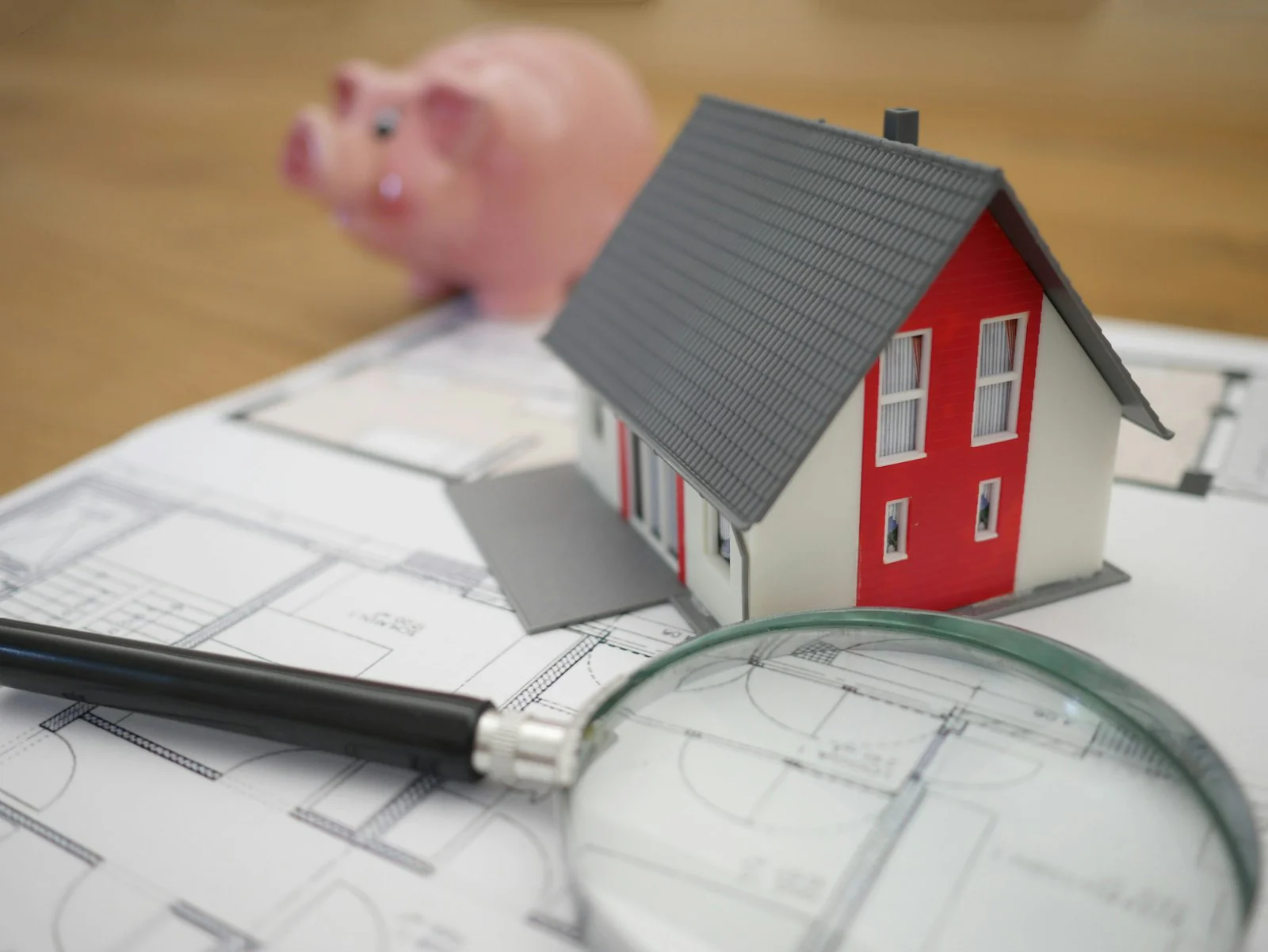 A model house on property plans beside a magnifying glass