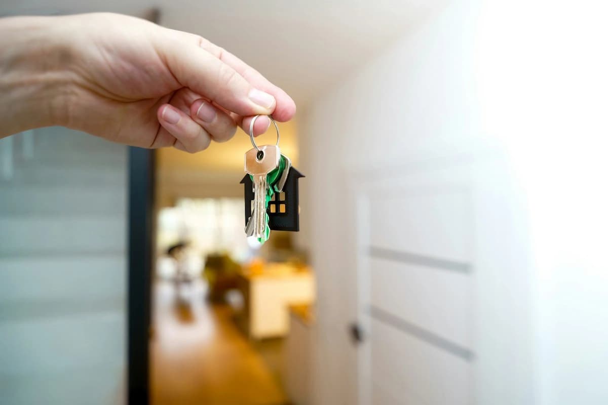 A hand holding out a set of house keys inside a home