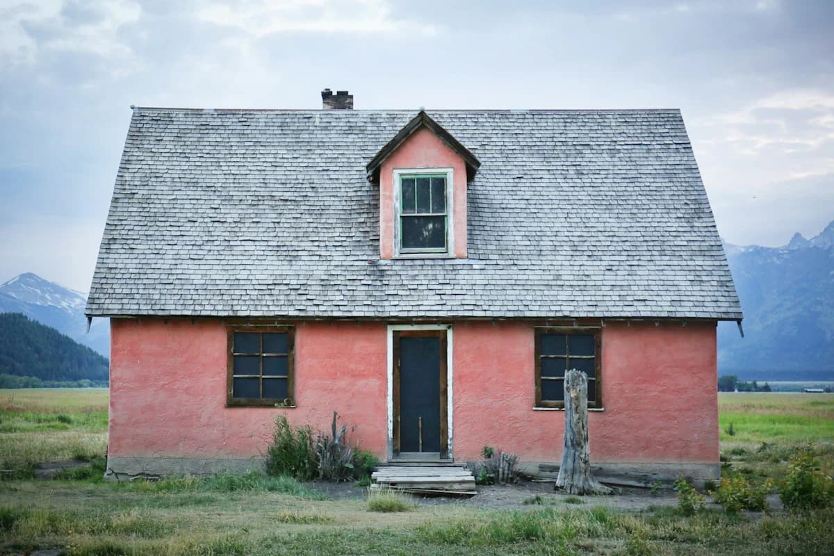 A weathered single-family house standing alone on open ground