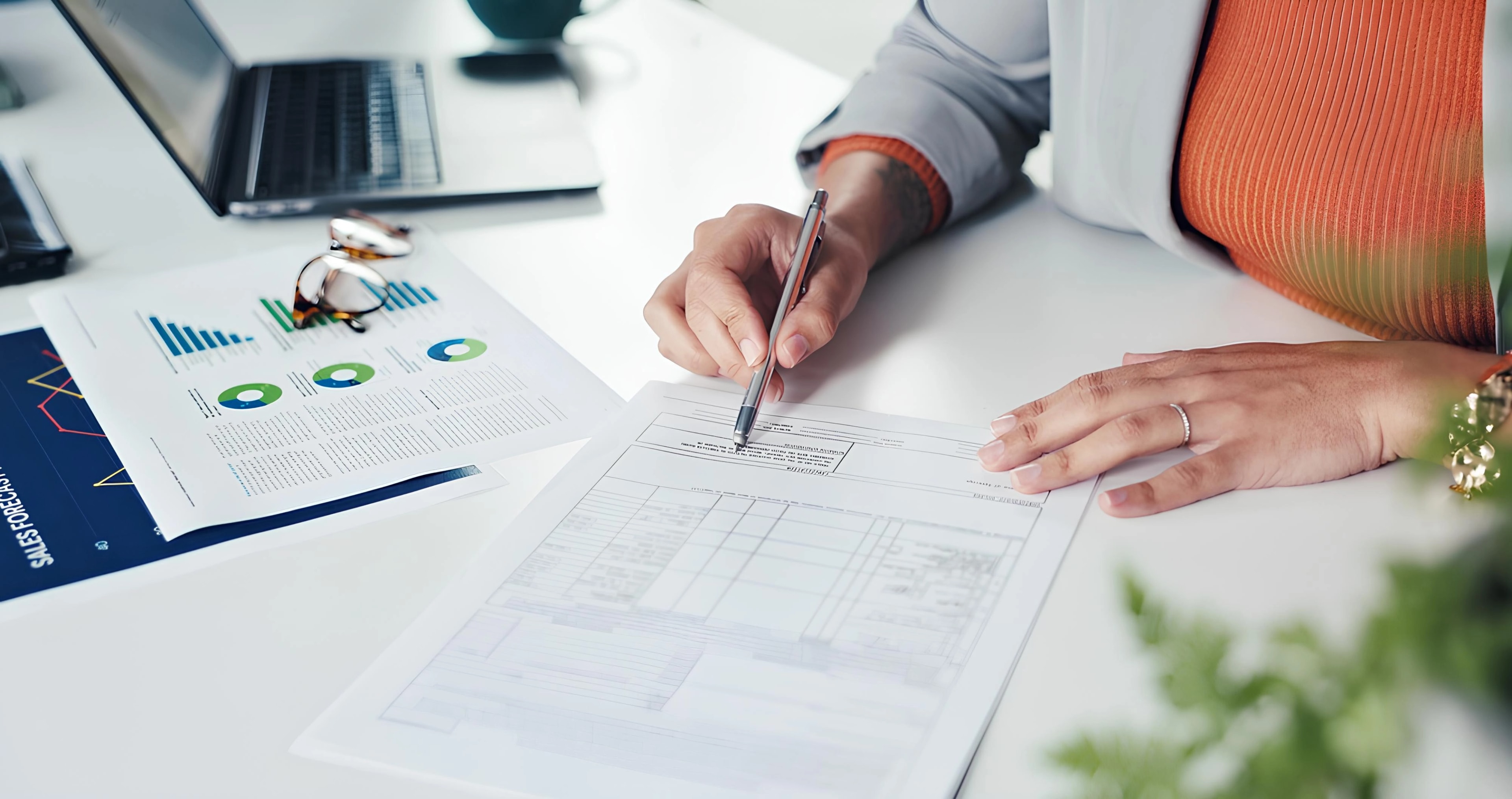 Hands reviewing and signing a loan document beside printed financial charts