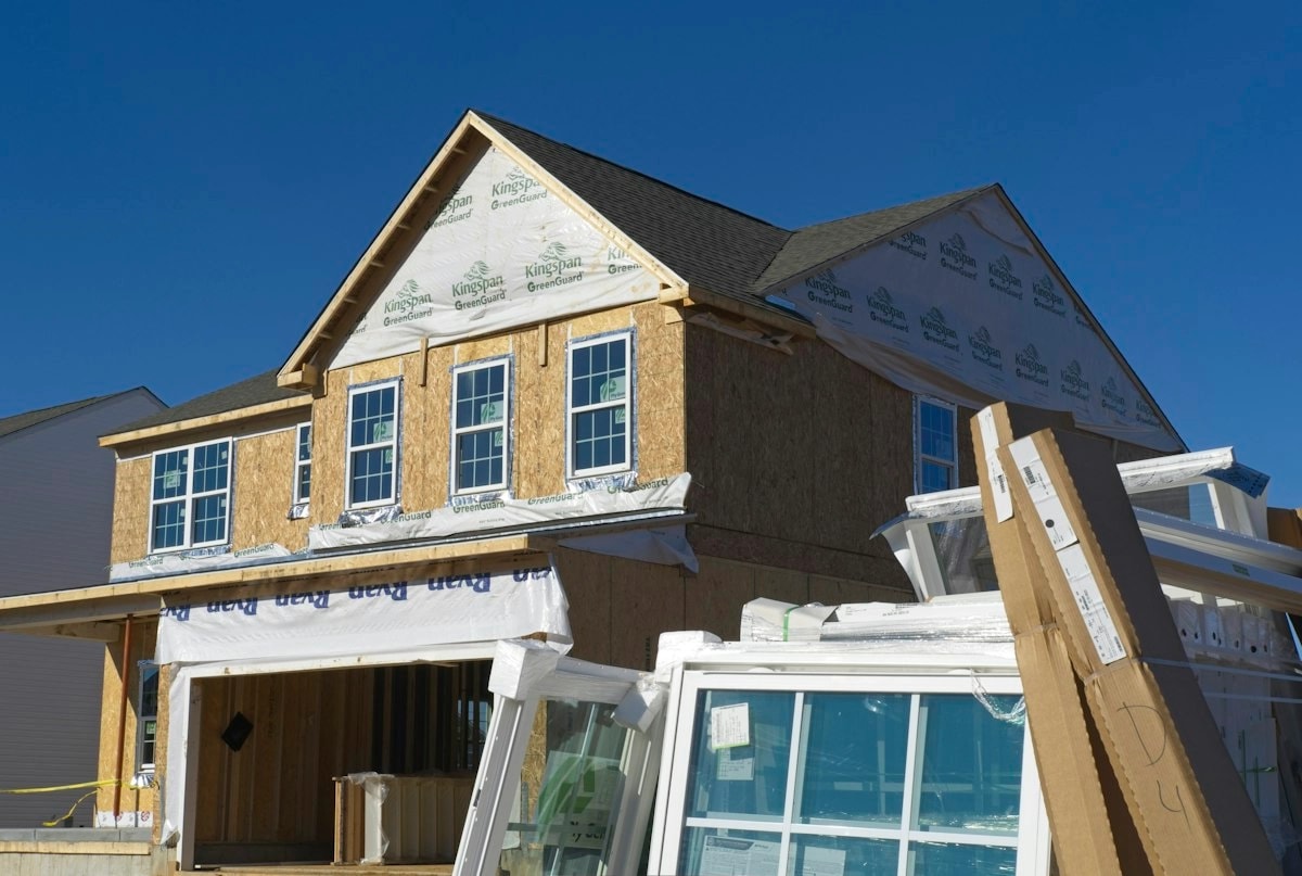 A new house under construction, its frame sheathed and windows waiting to be fitted