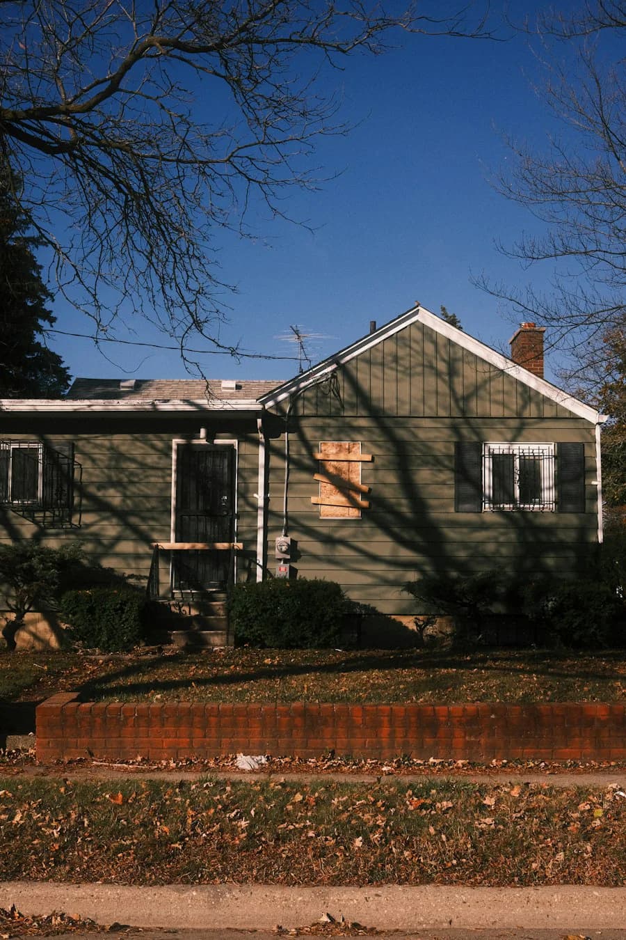A weathered house with a boarded-up window